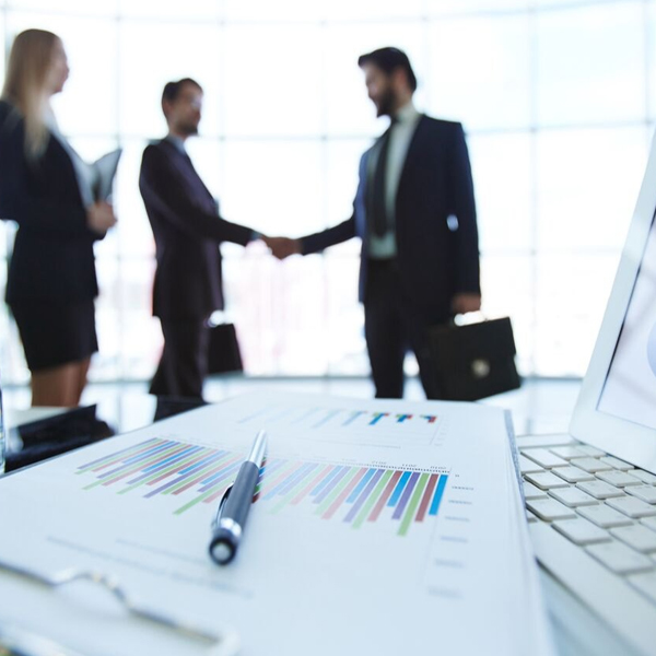 Consultants shake hands, finalizing business advisory services with charts