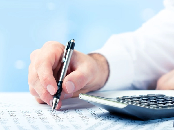 Payroll services with hand calculating financial data using pen and calculator