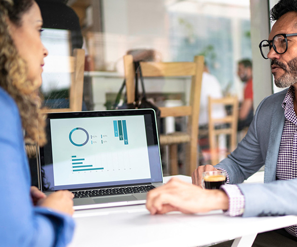 Two business people discuss charts on a laptop for SMSF Accounting Services