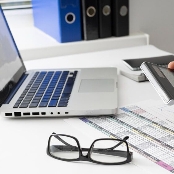 A professional's desk with a laptop, eyeglasses, and tax return forms